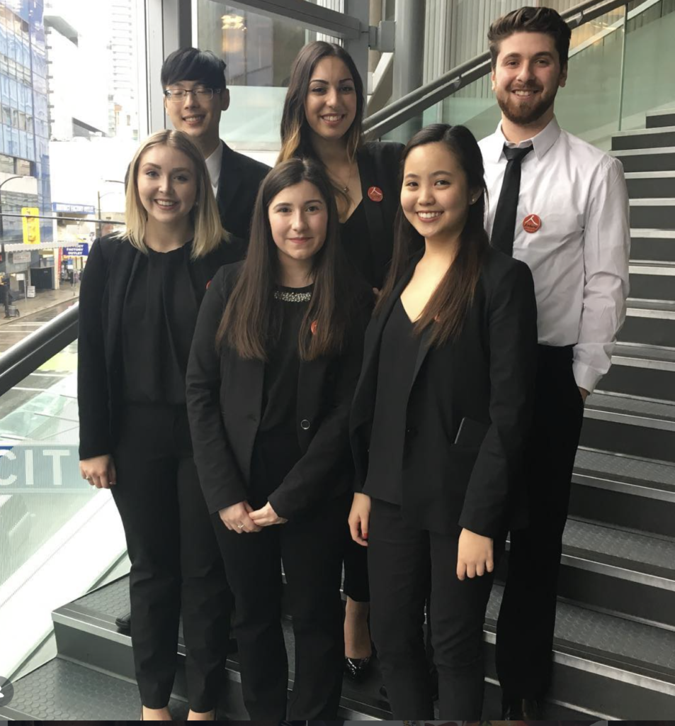 Group of young marketing professionals standing on the steps in their business attire.